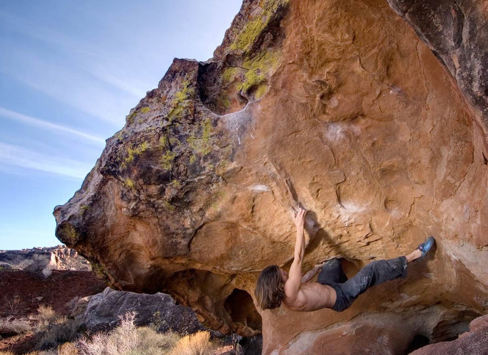 A climber pulling through the steep overhanging prow of Bazooka Tooth, a large sandstone boulder in Moe's Valley