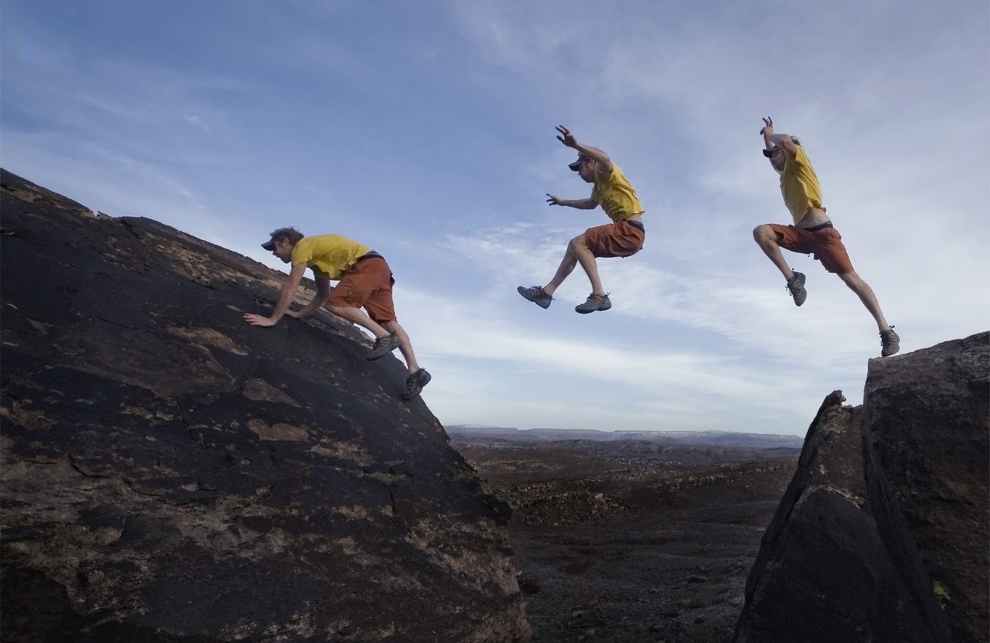 Sequence of a trail runner leaping between dark boulders above the valley